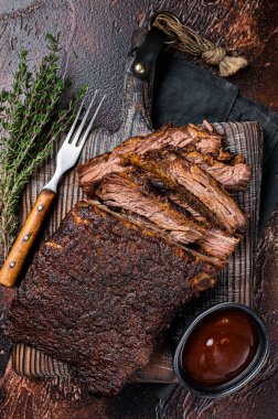 Traditional smoked barbecue wagyu beef brisket on wooden board. Dark background. Top view.