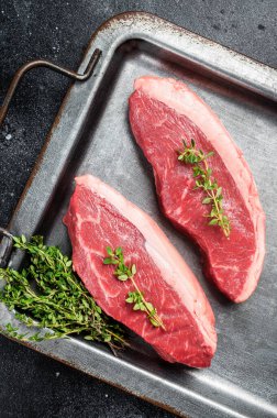 En iyi sığır filetosu, çelik tepside kekik ve biberli çiğ biftek. Siyah arka plan. Üst görünüm.