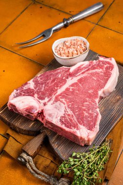Biftek, biftek, kekik ve ahşap tahtada deniz tuzu. Turuncu arka plan. Üst görünüm.