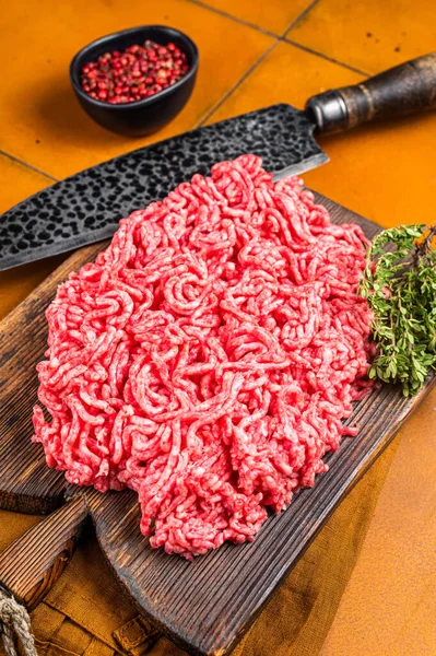 Fresh Raw Mince, Ground beef and pork meat on a butcher board. Orange background. Top view.