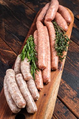 Raw homemade sausages with Beef, pork, lamb and chicken mince meat on a wooden board. Wooden background. Top view.