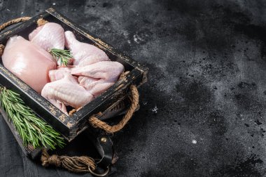 Fresh raw chicken meat and chicken parts - drumstick, breast fillet, wing, thigh. Black background. Top view. Copy space.