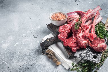 Butcher cutting board with butchered Raw Lamb chop steak or mutton cutlet. Gray background. Top view. Copy space.