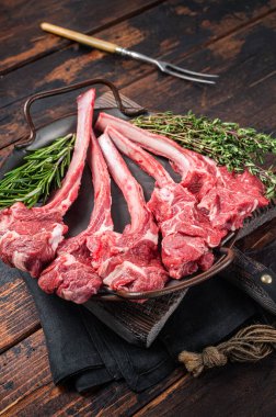 Fresh Raw Lamb chop steak in steel tray with herbs. Wooden background. Top view.