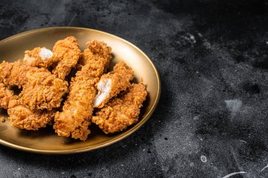 Breaded chicken strips, breast fillet meat on a plate. Black backgrund. Top view. Copy space.