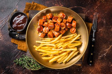 Alman körili sosisi, körili sosis ve patates kızartması. Karanlık arka plan. Üst görünüm.