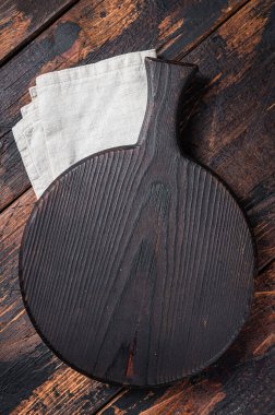 Black wooden Cutting board over towel on kitchen table. Wooden background. Top view. Copy space.