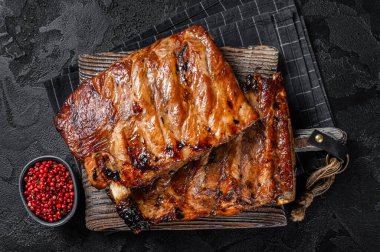 BBQ soslu domuz pirzolası dilimleme tahtasında. Siyah arka plan. Üst görünüm.