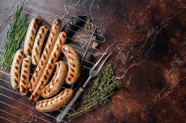 Assortment of different bbq grilled sausages with Beef, pork, lamb and chicken meat on a grill. Dark background. Top view. Copy space.