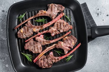 Fried on a grill skillet lamb cutlet steak, mutton rib chop. Gray background. Top view.