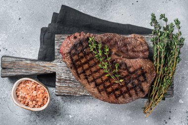 Roasted on grill top sirloin steak with rosemary and thyme. Gray background. Top view. clipart