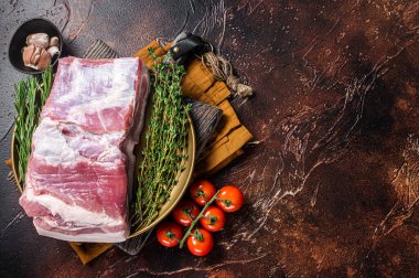 Farm fresh Pork belly, raw meat in a plate with spices. Dark background. Top view. Copy space.