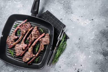 Fried on a grill skillet lamb cutlet steak, mutton rib chop. Gray background. Top view. Copy space.
