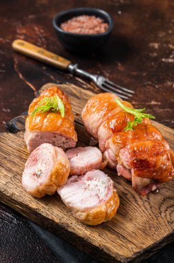 Roast Chicken roll with cheese and herbs on a wooden board. Dark background. Top view.
