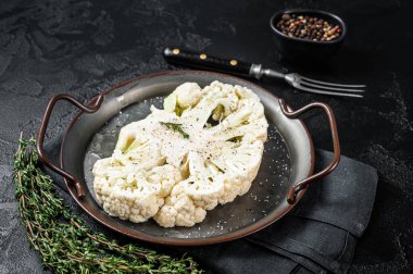 Vegetarian cuisine - cooking of cauliflower steak. Black background. Top view.