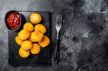 Creamy Mashed Potato Croquettes with Cheese served on a marble board. Black background. Top view. Copy space.