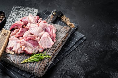 Raw chicken stomachs, giblets gizzards on a butcher board with meat cleaver. Black background. Top view. Copy space.