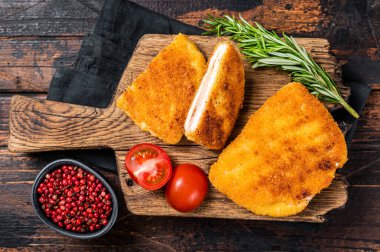Crispy Cordon Blue Chicken fillet roll with ham and cheese served on a wooden board. Wooden background. Top view.