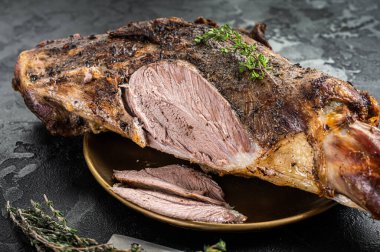 Christmas dish - Roast lamb leg meat with spices and thyme on a plate. Black background. Top view.