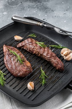 Roasted on a grill skillet Flank flap or Bavette beef meat steak with rosemary. Gray background. Top view.