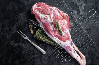 Marinated raw lamb mutton Leg Thigh with thyme and spices. Black background. Top view.