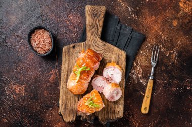 Roast Chicken roll with cheese and herbs on a wooden board. Dark background. Top view.