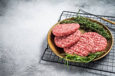 Çiğ kıymalı biftek, çelik tabakta baharat, biberiye ve kekik. Beyaz arka plan. Üst Manzara. Boşluğu kopyala.