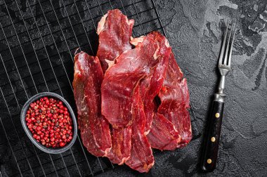 Dried sliced basturma, cured beef meat ready for eat. Black background. Top view.