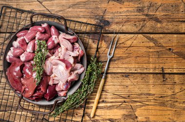 Raw bird giblets meat set, chicken offals, liver, hearts, gizzards Stomach. Wooden background. Top view. Copy space.