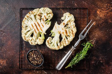 Grilled cauliflower steak with rosemary and spices, Vegan cuisine. Dark background. Top view.