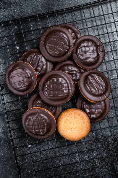 Jaffa Cakes, Cookies covered with dark chocolate and filled with orange marmalade. Black background. Top view.