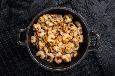 Roasted Shrimps with garlic, olive oil and spices in a skillet. Black background. top view.