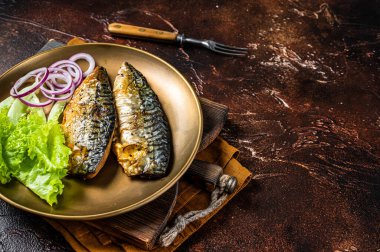 Grilled mackerel scomber fish fillets with garnish in a plate. Dark background. Top view. Copy space.