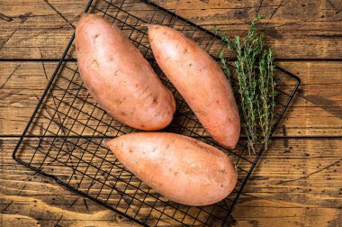 Raw sweet potatoes on kitchen table, fresh batata. Wooden background. Top view.
