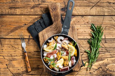 Cooking of fresh seafood mix in a skillet. Wooden background. Top view.