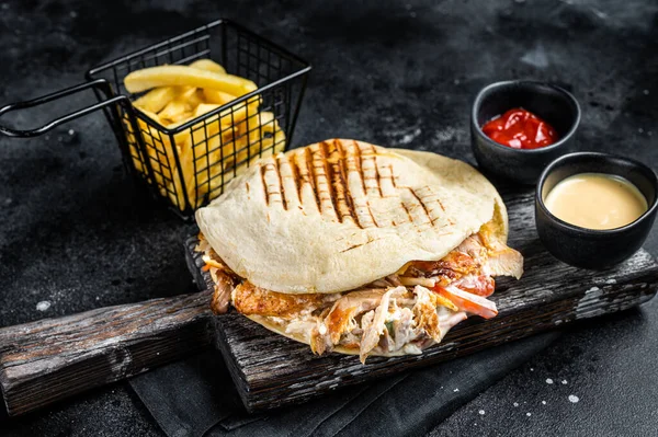 Turkish doner kebab in grilled pita bread with chicken meat. Black background. Top view.