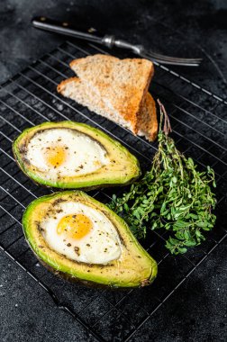 Cooking Baked Avocado with Egg. Black background. Top view.