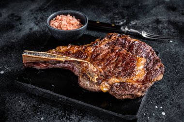 Grilled cowboy or rib eye with bone beef steak. Black background. Top view.