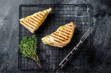 Grilled panini with Prosciutto ham, salad and cheese. Black background. top view.