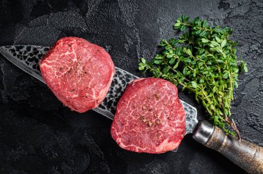 Fillet Mignon Beef steak, raw dry aged marble meat. Black background. Top view.