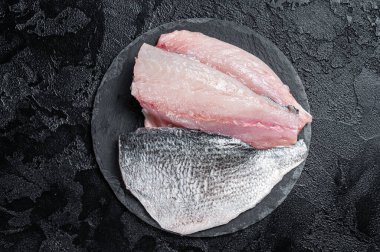 Raw Sea bream Dorado fish fillets. Black background. Top view.