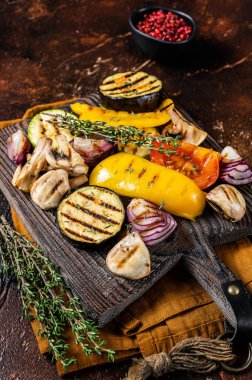 Summer BBQ with grilled Vegetables, bell pepper, zucchini, eggplant, onion and tomato on a wooden board. Dark background. Top view.