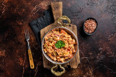 Turkish Menemen omelet with vegetabls and sucuk in askillet. Dark background. Top view.