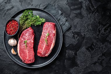 Dry aged Raw top blade flat Iron beef meat steaks. Black background. Top View. Copy space.