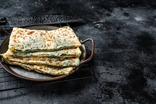 Gozleme Turkish flatbread with greens and cheese. Black background. Top view. Copy space.