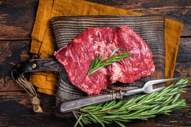 Raw alternative skirt beef steak on butcher board. Wooden background. Top view.