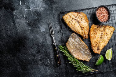 Baked Dorado Sea Bream fillets. Black background. Top view. Copy space.