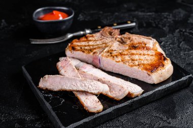 Grilled slised pork Chop or T-bone meat steak. Black background. Top view.