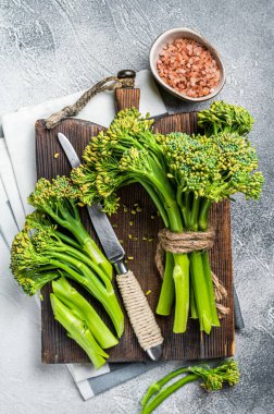 Fresh bunch of Broccolini sprouts on cutting board ready for cookining. White background. Top view.