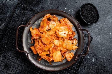 Chinese cabbage kimchi in black dish, Korean cuisine. Black background. Top view.